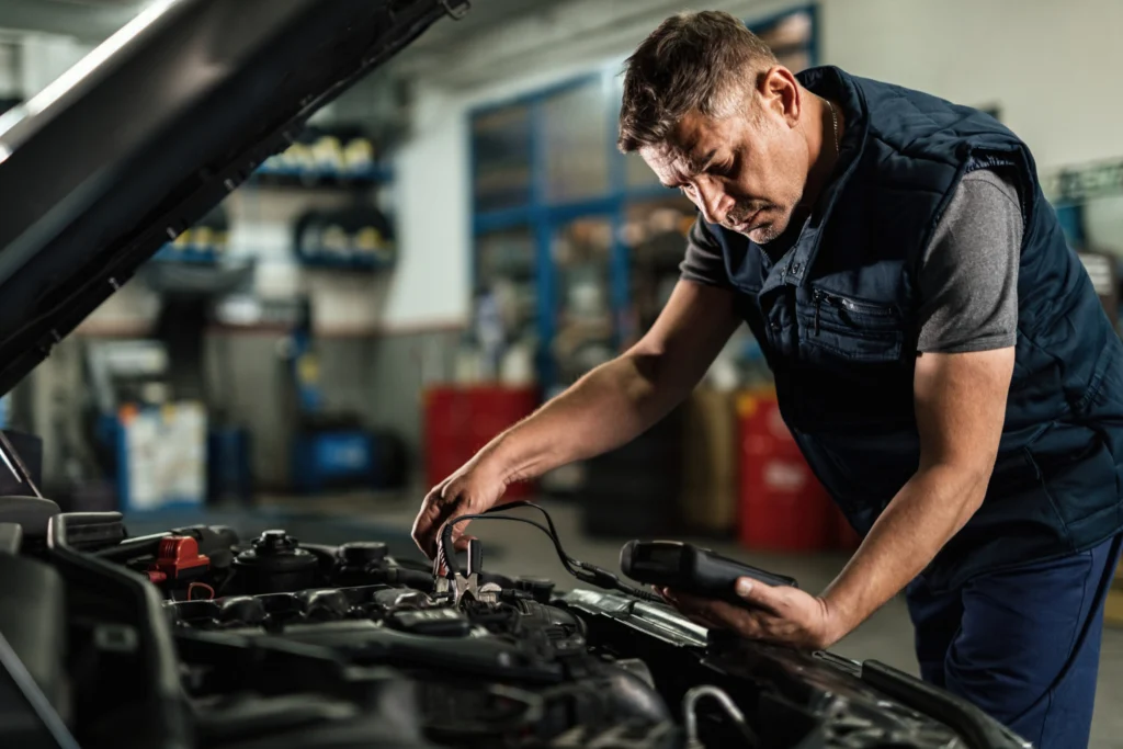 auto-mechanic-using-diagnostic-tool-while-checking-car-battery-voltage-workshop-scaled