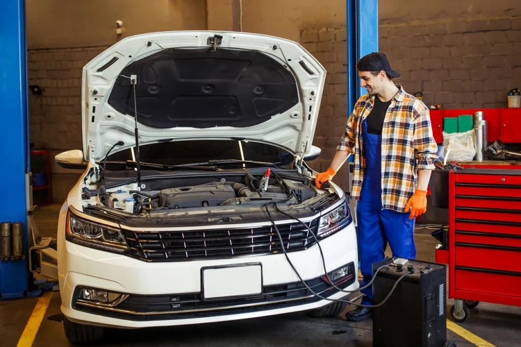 full-length-shot-handsome-auto-mechanic-charging-battery-using-wire-cables-modern-service-station