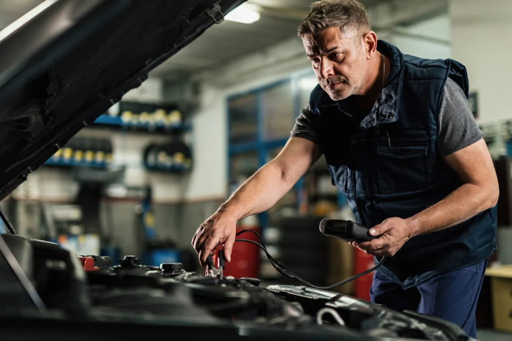 mid-adult-mechanic-using-diagnostic-tool-while-checking-voltage-car-battery-auto-repair-shop-scaled